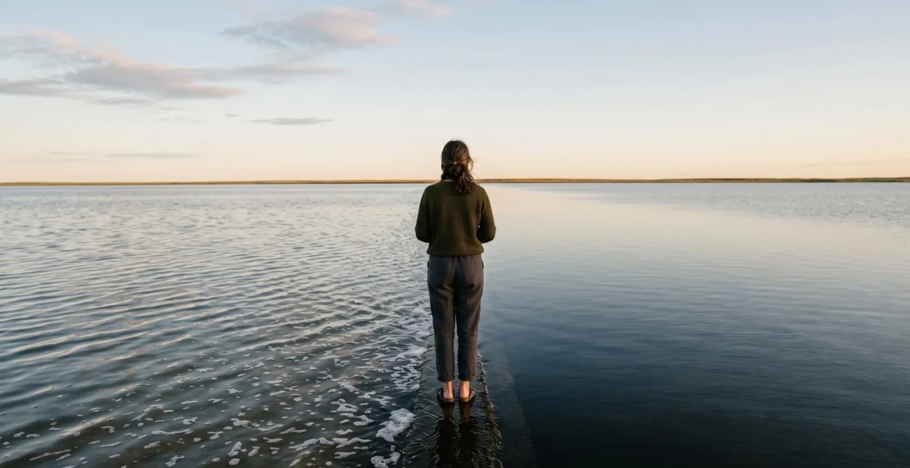 Une personne debout à la limite entre une eau calme et une eau agitée, symbolisant l'équilibre émotionnel entre étouffer et laisser exploser ses émotions